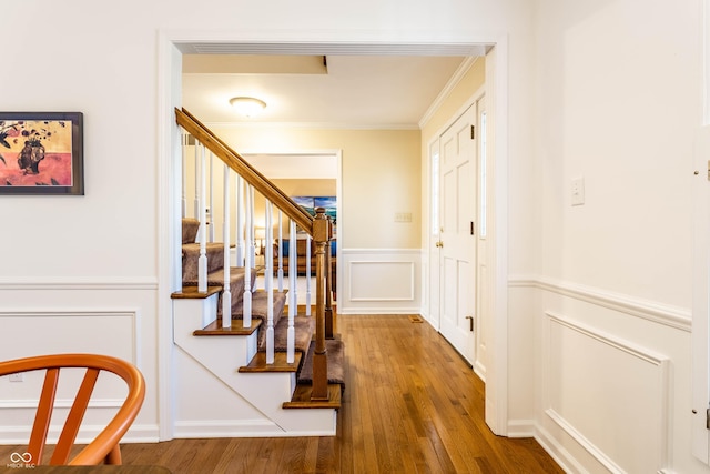 interior space with a decorative wall, a wainscoted wall, crown molding, and hardwood / wood-style flooring