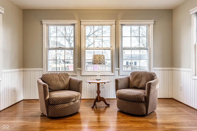 living area with a wealth of natural light, wood finished floors, and wainscoting