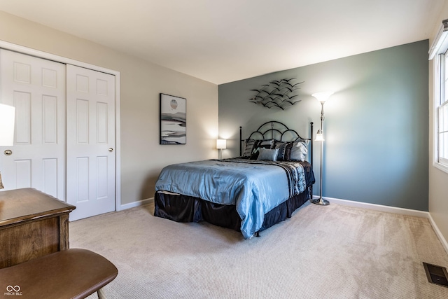 carpeted bedroom featuring visible vents, baseboards, and a closet