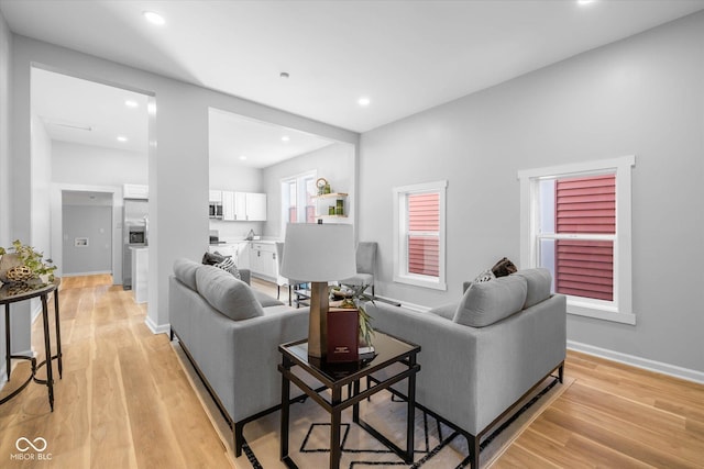 living room with recessed lighting, baseboards, and light wood-style flooring