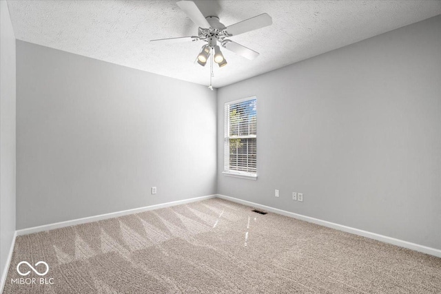 carpeted spare room with visible vents, baseboards, and a textured ceiling