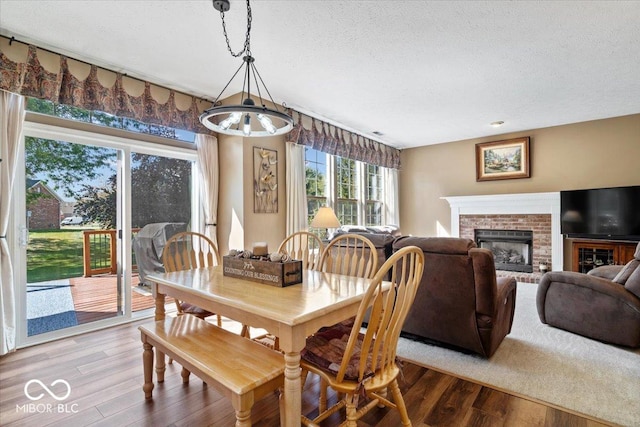 dining space featuring a fireplace, wood finished floors, and a textured ceiling