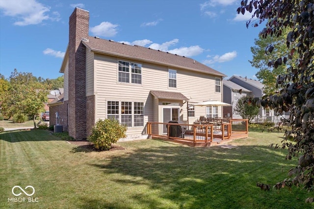 rear view of house with a yard, a wooden deck, and a chimney