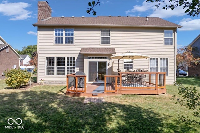 rear view of property with a wooden deck, a chimney, and a yard