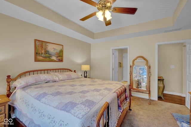 bedroom with a tray ceiling, baseboards, carpet floors, and ceiling fan