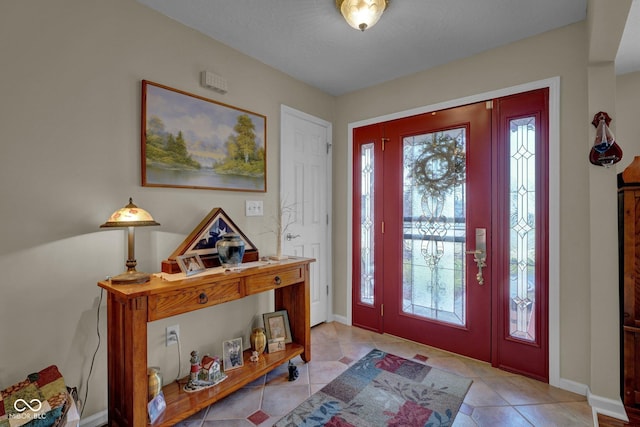 entryway with light tile patterned flooring, a healthy amount of sunlight, and baseboards