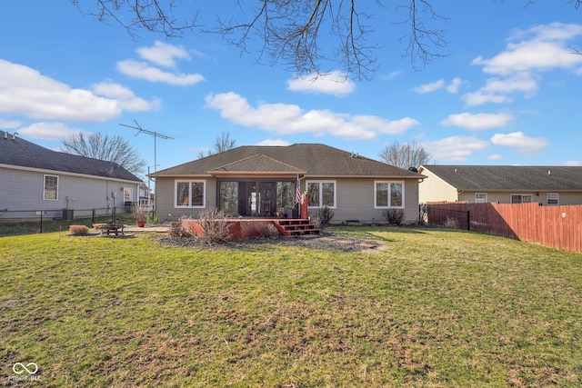 rear view of house featuring a yard, a fire pit, a fenced backyard, and a sunroom