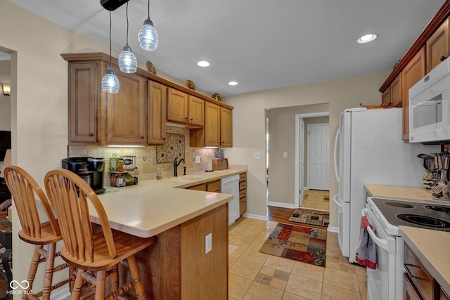 kitchen featuring light countertops, decorative backsplash, hanging light fixtures, white appliances, and a sink