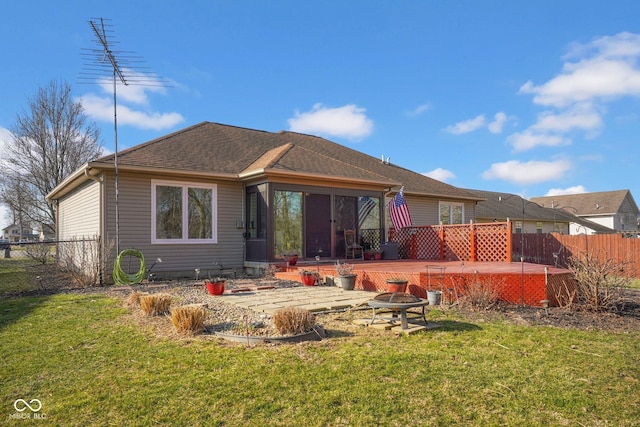 back of house featuring a fire pit, fence, a lawn, and a wooden deck