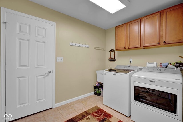 washroom featuring washer and dryer, baseboards, cabinet space, and light tile patterned floors