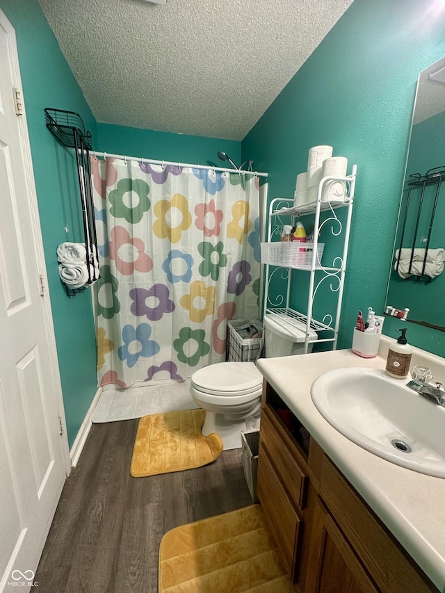 full bathroom with vanity, a shower with shower curtain, wood finished floors, a textured ceiling, and toilet