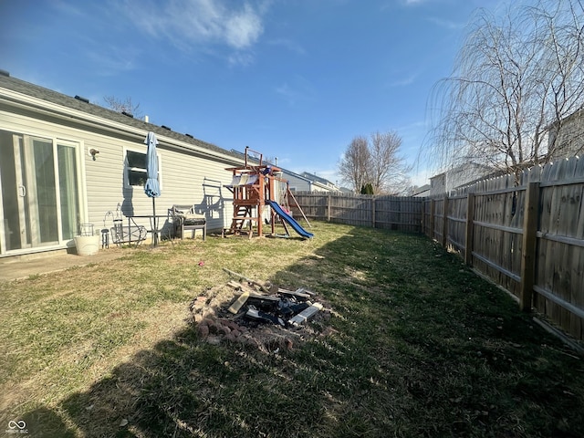 view of yard featuring an outdoor fire pit, a fenced backyard, and a playground