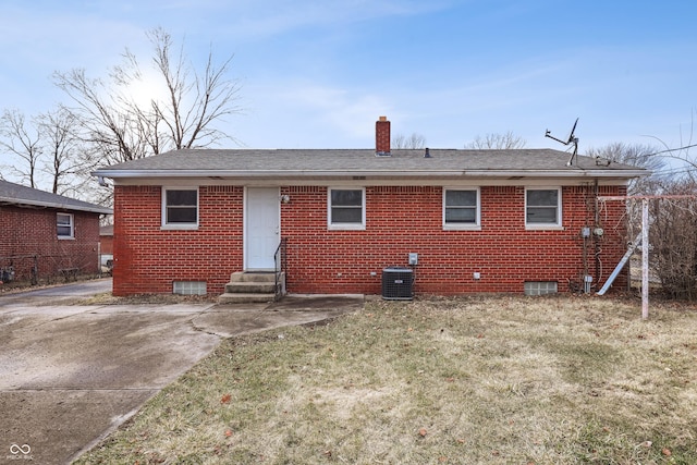 back of property with cooling unit, a yard, a chimney, entry steps, and brick siding