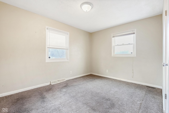 carpeted spare room with visible vents and baseboards