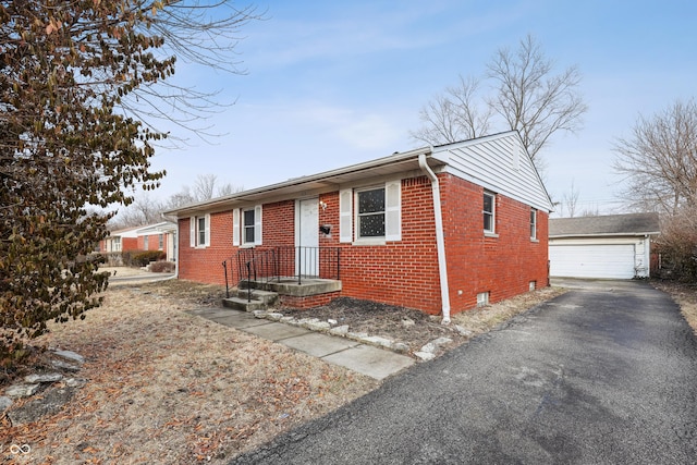 view of front of home with brick siding, a garage, an outdoor structure, and crawl space