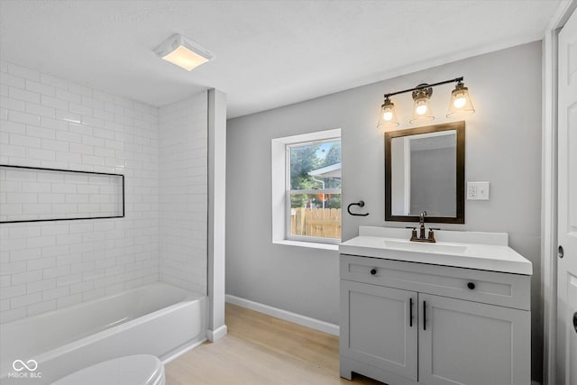 bathroom with baseboards, toilet, wood finished floors, and vanity