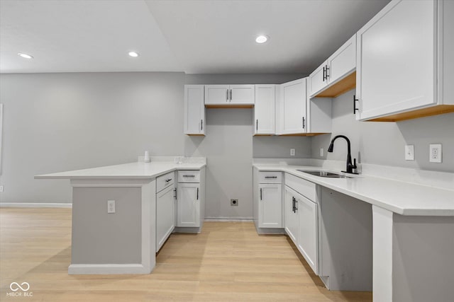 kitchen featuring light wood finished floors, recessed lighting, light countertops, and a sink