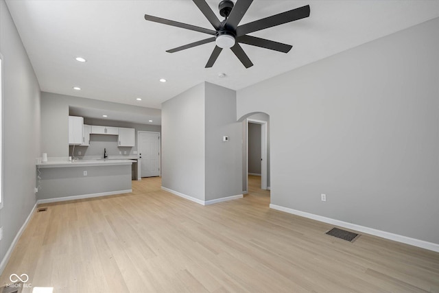 unfurnished living room featuring visible vents, baseboards, recessed lighting, arched walkways, and light wood-style floors