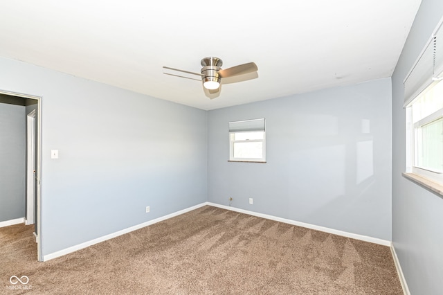 carpeted spare room with baseboards and a ceiling fan