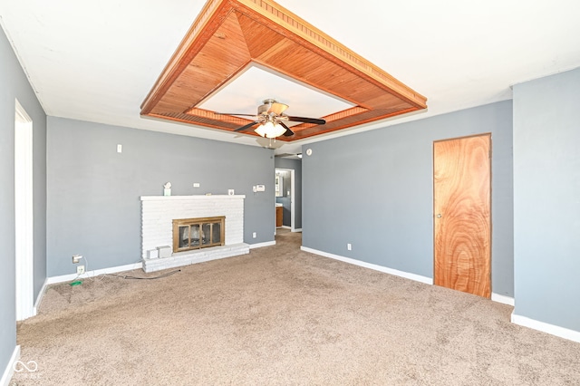 unfurnished living room with a fireplace, baseboards, carpet, and a tray ceiling