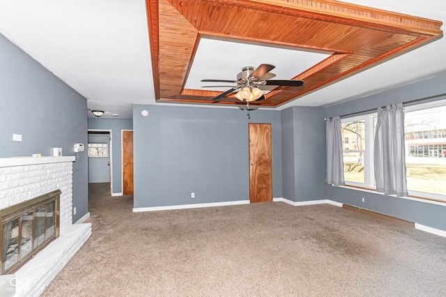 unfurnished living room featuring a tray ceiling, a brick fireplace, wood ceiling, and baseboards