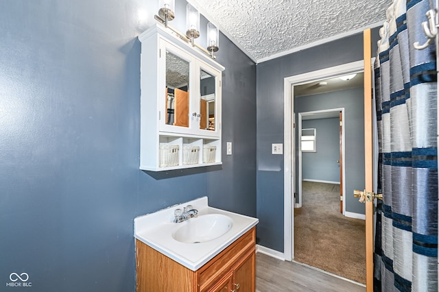 bathroom featuring baseboards, a textured ceiling, wood finished floors, and vanity