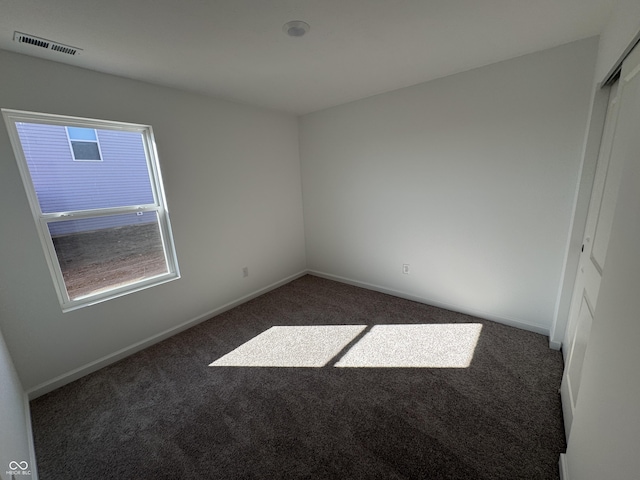 carpeted empty room featuring visible vents and baseboards