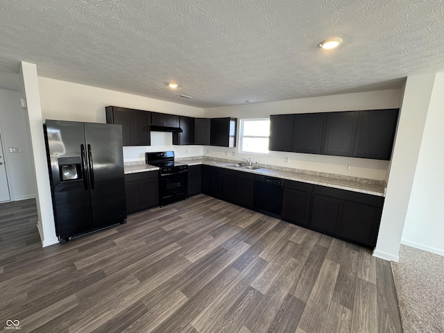 kitchen with a sink, black appliances, light countertops, under cabinet range hood, and dark cabinets