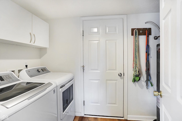 washroom featuring wood finished floors, cabinet space, and washing machine and dryer