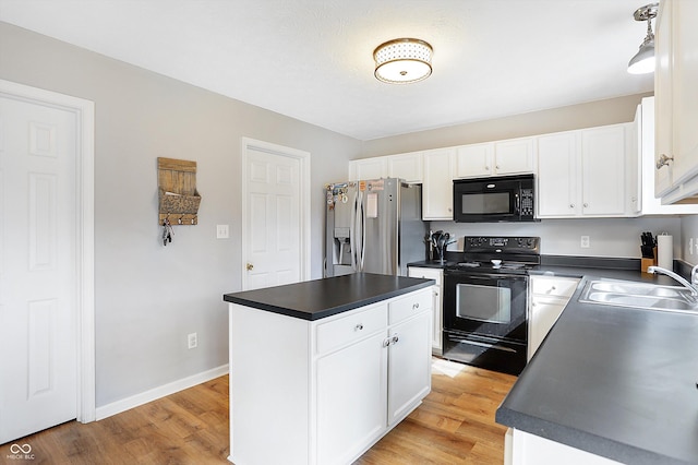 kitchen featuring black appliances, dark countertops, light wood finished floors, and a sink