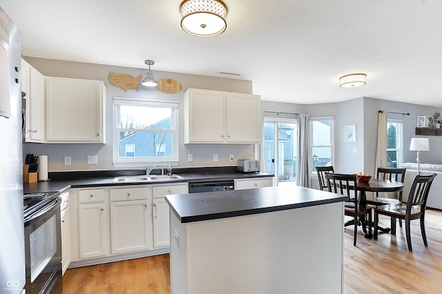 kitchen featuring dark countertops, visible vents, black range with electric cooktop, light wood-type flooring, and a sink