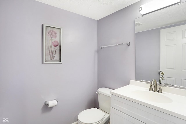 bathroom featuring vanity, toilet, visible vents, and a textured ceiling