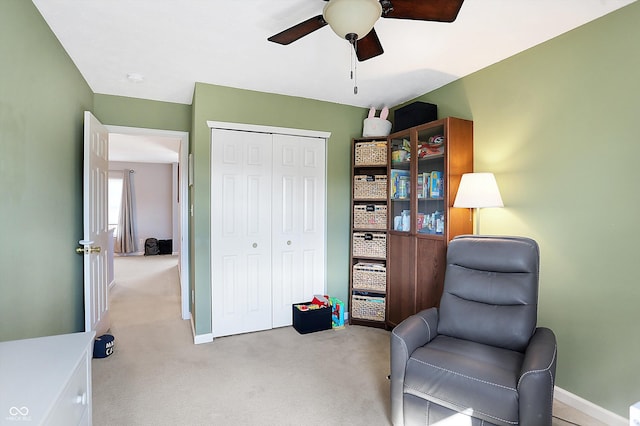 living area with light carpet, ceiling fan, and baseboards