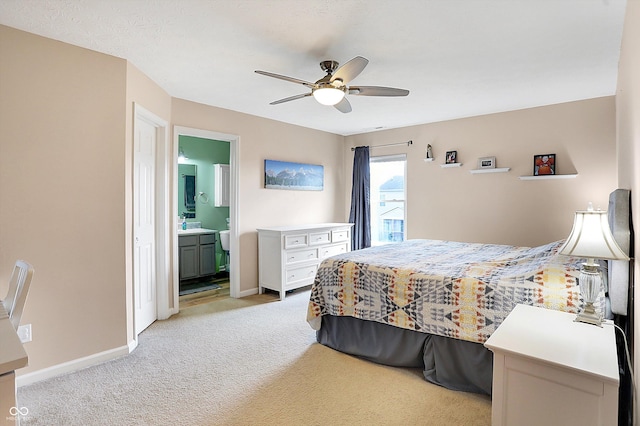 bedroom featuring ceiling fan, ensuite bath, baseboards, and light carpet