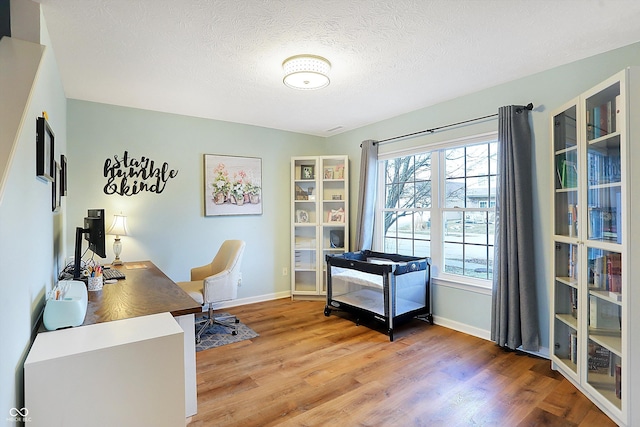 home office featuring baseboards, a textured ceiling, and light wood finished floors