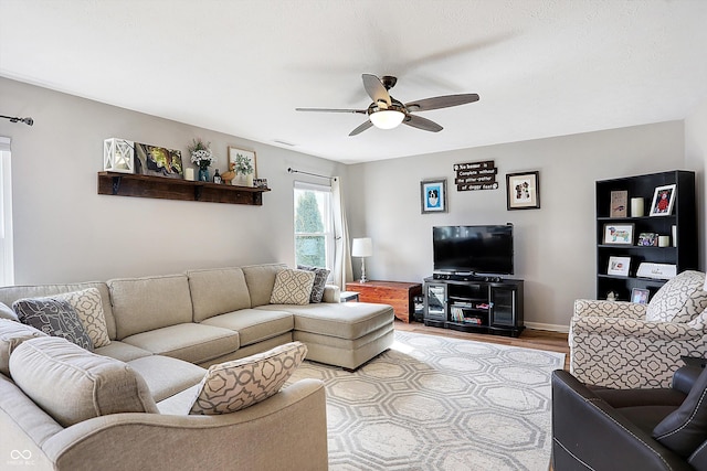 living area with visible vents, wood finished floors, baseboards, and ceiling fan