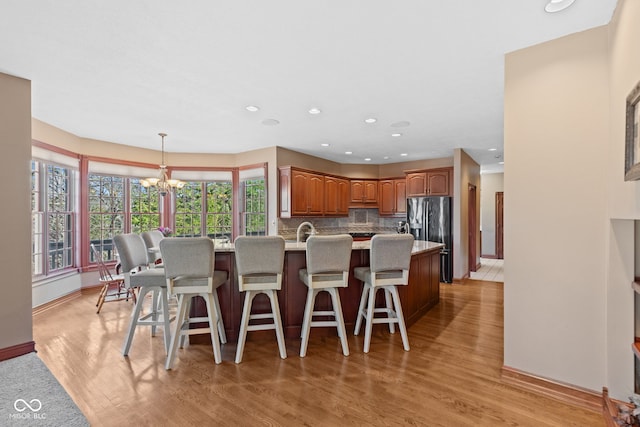 dining area with recessed lighting, baseboards, light wood-type flooring, and an inviting chandelier