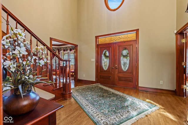 entrance foyer featuring stairway, a high ceiling, baseboards, and wood finished floors