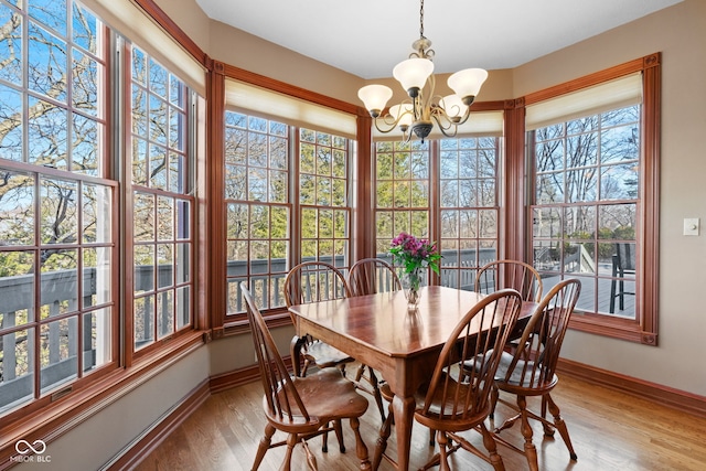 dining room with light wood-type flooring, baseboards, and a notable chandelier