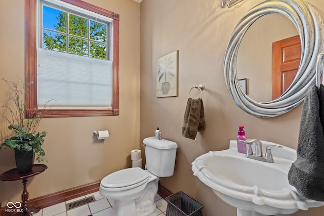 half bathroom featuring tile patterned floors, visible vents, toilet, a sink, and baseboards