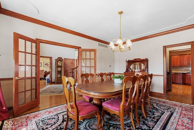 dining area with visible vents, french doors, light wood-style floors, an inviting chandelier, and crown molding