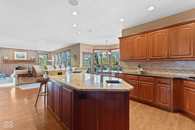 kitchen with a sink, light wood-type flooring, a breakfast bar, and a fireplace