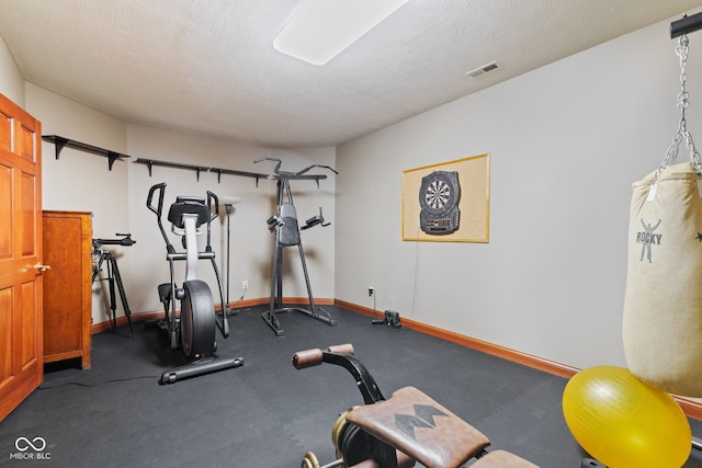 exercise room with visible vents, a textured ceiling, and baseboards