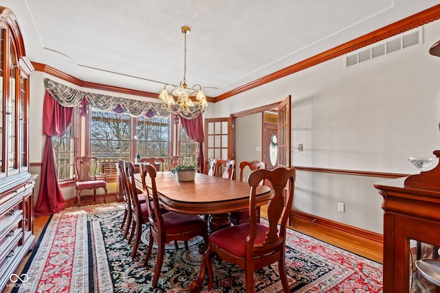 dining room with visible vents, crown molding, baseboards, a chandelier, and wood finished floors