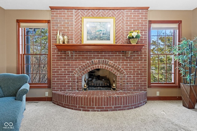 carpeted living room featuring baseboards and a brick fireplace