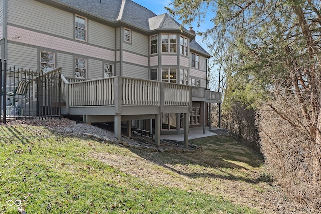 rear view of property with a yard, a shingled roof, a wooden deck, and a patio area