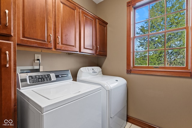 clothes washing area with washer and clothes dryer, cabinet space, and baseboards