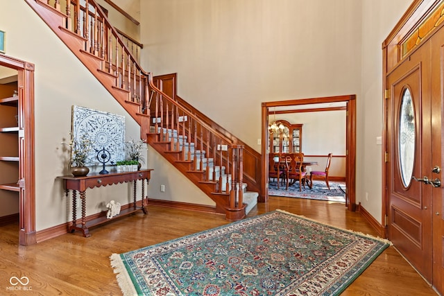 entrance foyer with baseboards, a high ceiling, wood finished floors, and stairs