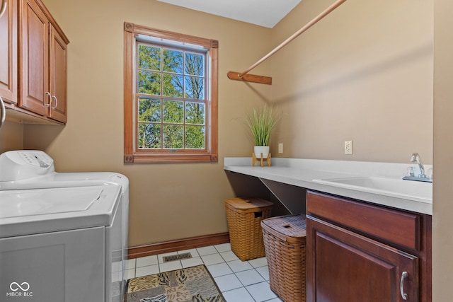 washroom featuring visible vents, light tile patterned floors, washer and dryer, cabinet space, and a sink
