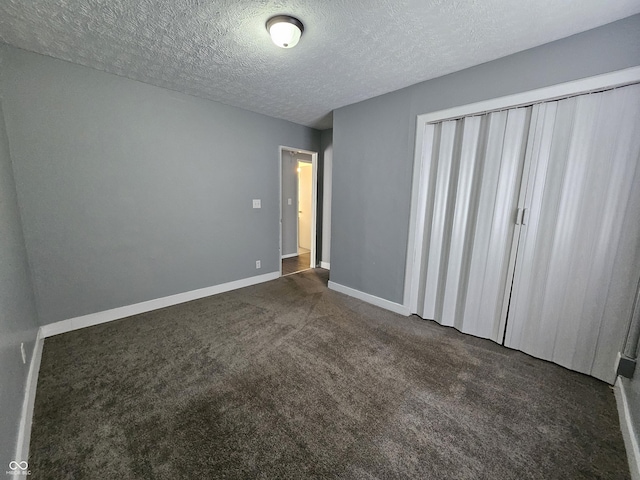 unfurnished bedroom with dark colored carpet, baseboards, and a textured ceiling